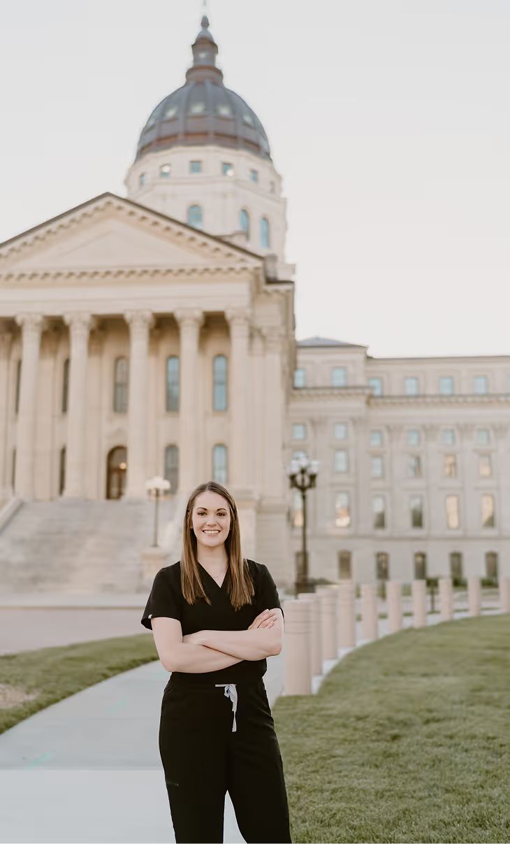 Dr. Heather Triggs in black scrubs in front of the Kansas State Capitol in Topeka